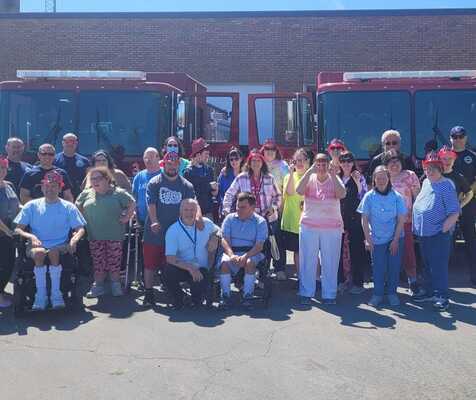 Staff and participants at fire station with fire trucks