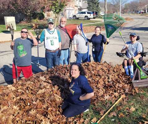 Participants and staff raking leaves for people in their community