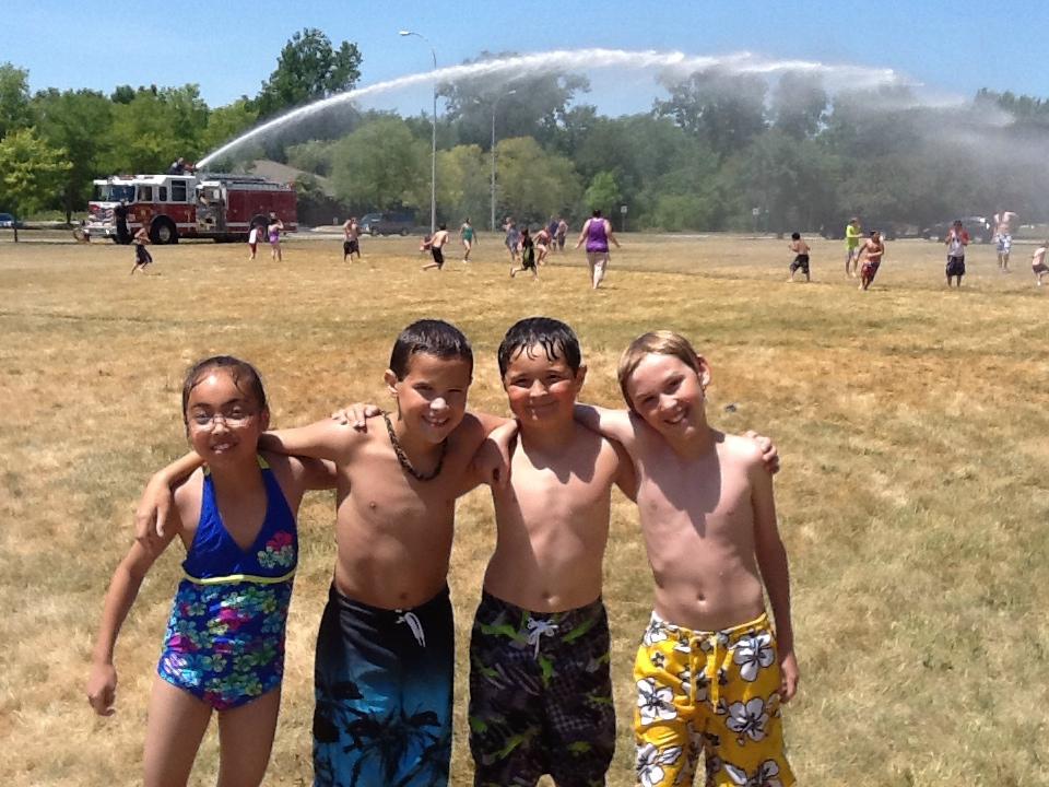 kids being sprayed by a firetruck