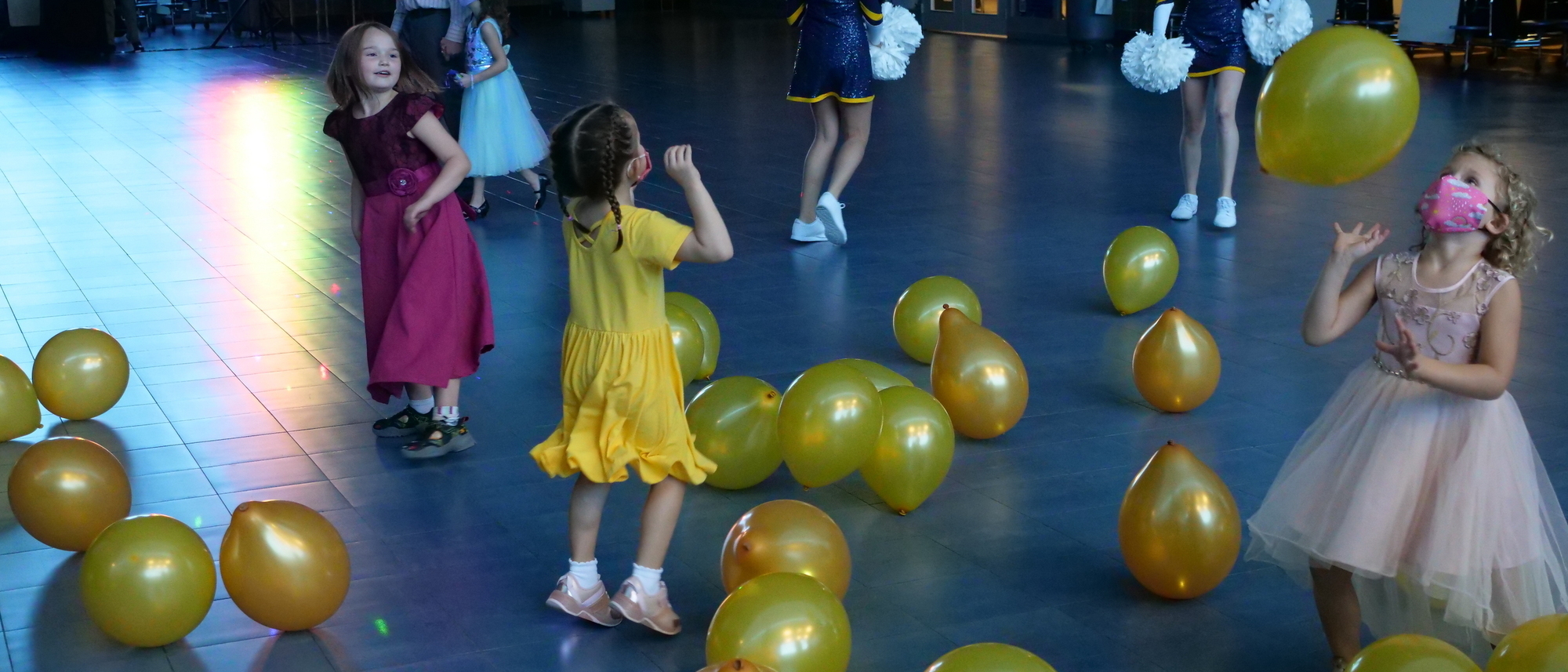 Girl in yellow dress dancing with yellow balloons.